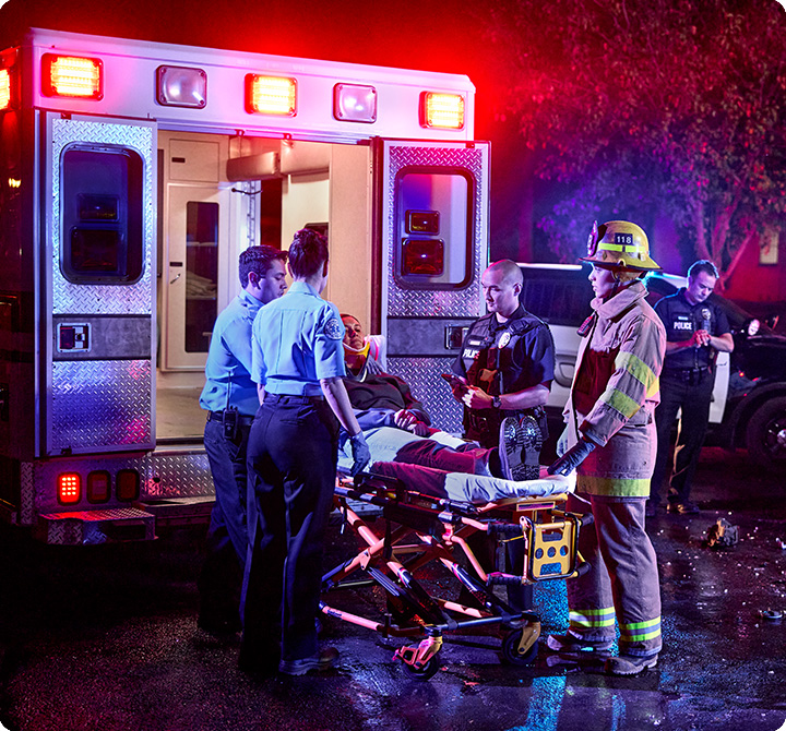 Multiple EMS first responders loading a patient on stretcher into an ambulance
