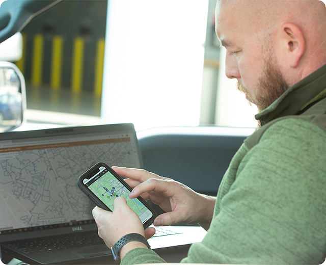 Utility employee using connected devices in car, out in the field 