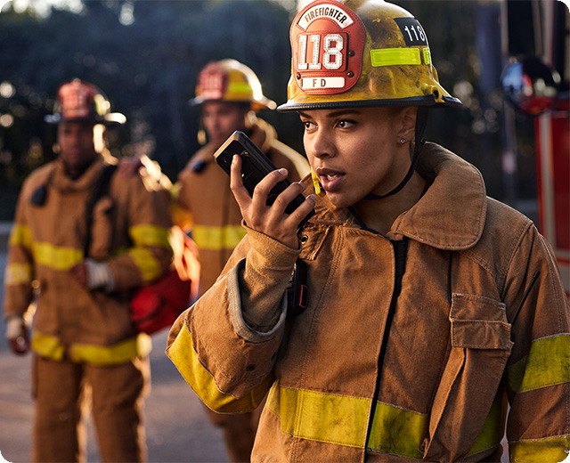 Female firefighters using push-to-talk firstnet phone to coordinate with first responders 