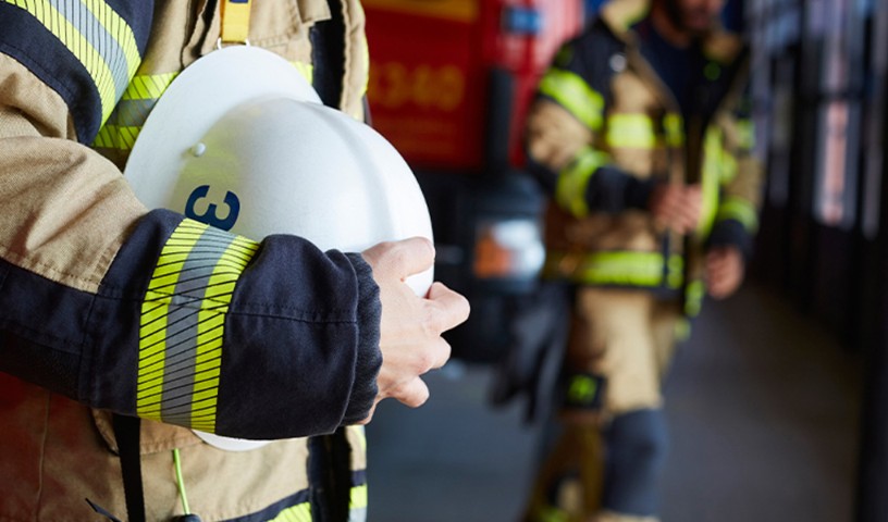 Closeup of firefighter clutching his hard hat to his chest with his right hand, preparing to leave firehouse