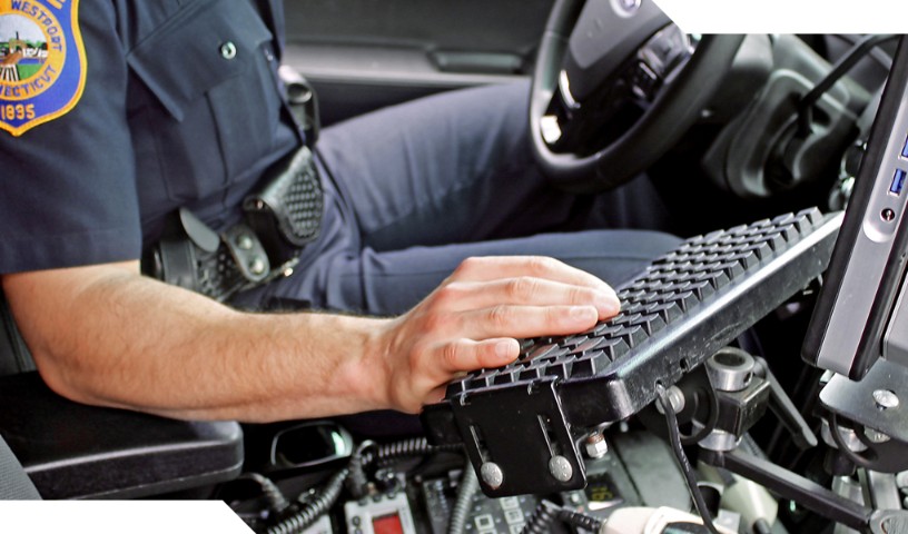 Westport policeman in car with right hand on keyboard